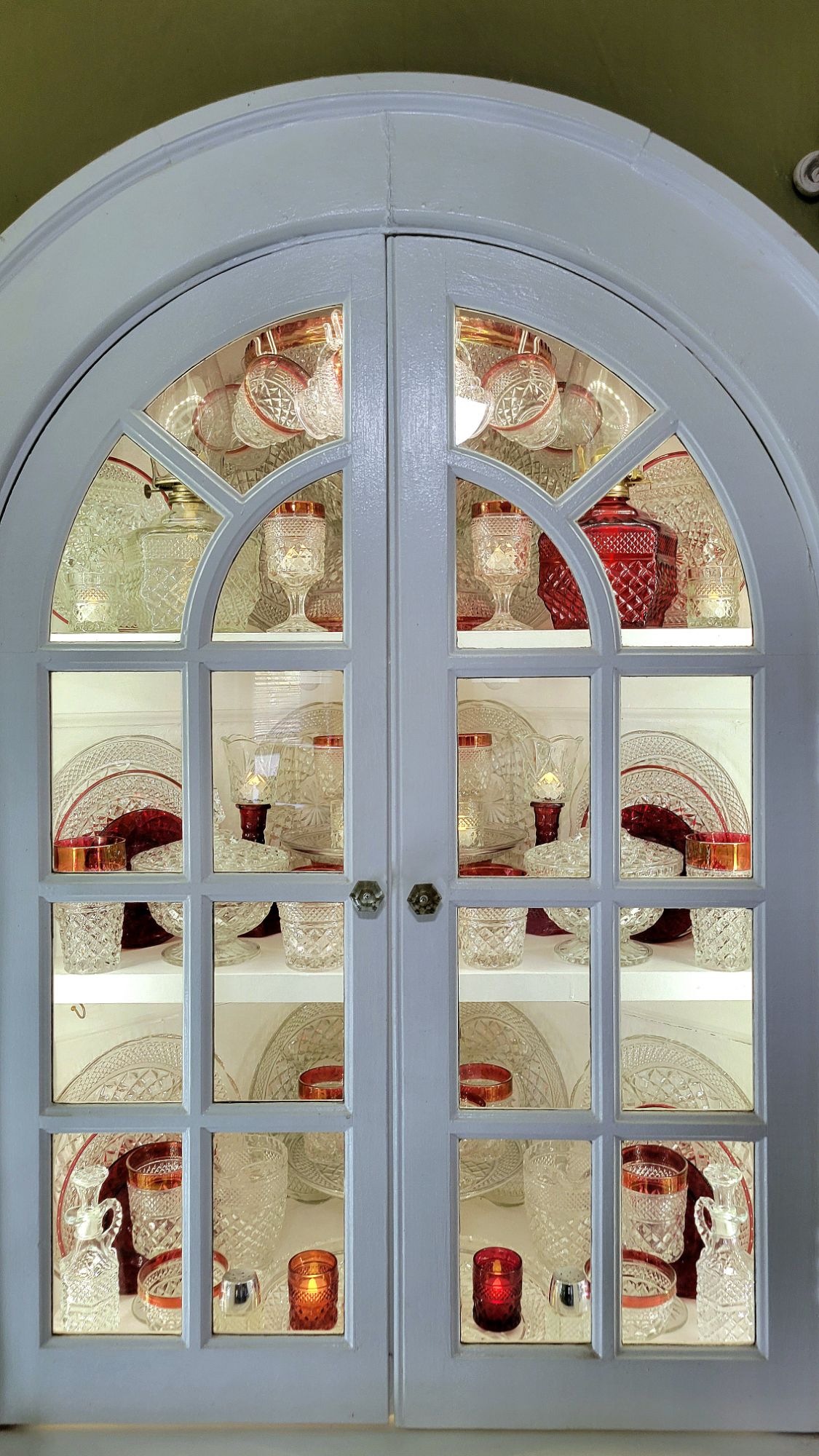 a built-in arched door hutch full of clear Wexford and ruby-banded Oxford glassware by Anchor Hocking. 