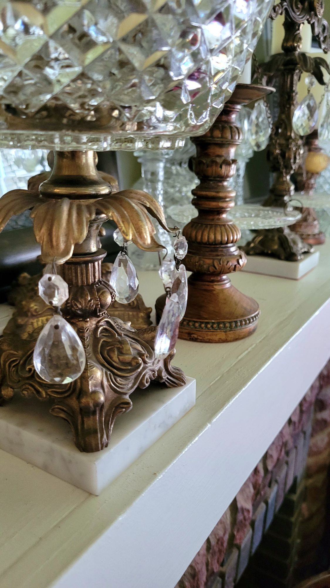 a close-up of the pedestal dish, showing details of the pedestal. details of other glassware and candlesticks can be seen behind it.