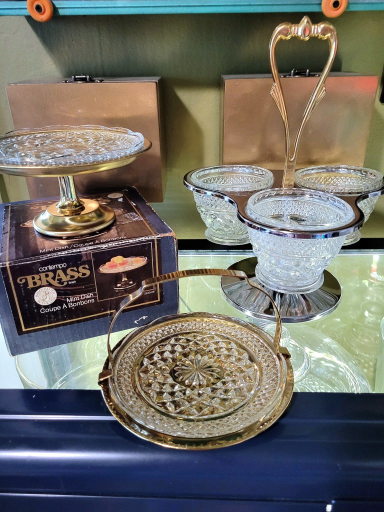 a grouping of Kromex servers: a brass pedestal mint dish with Wexford ddessert plate, a brass handled tray with Wexford dessert plate, and a brass handled chrome condiment server refit with Wexford sugar bowls.