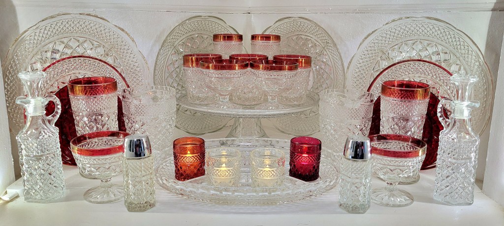 an assortment of ruby-banded glassware, red flashed votives, and various clear glass pieces from the Anchor Hocking Wexford line, as well as royal ruby dessert plates, also from AH.