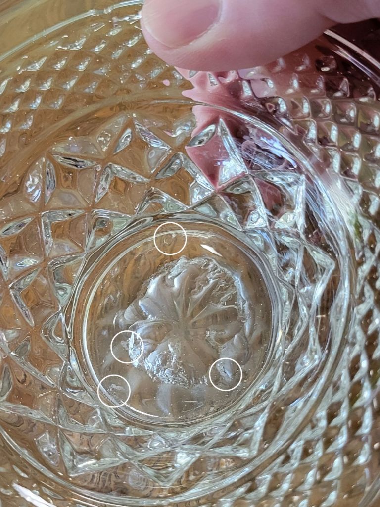 a close-up view of a pressed glass basket base, mimicking Wexford by Anchor, showing flaws in the glass.