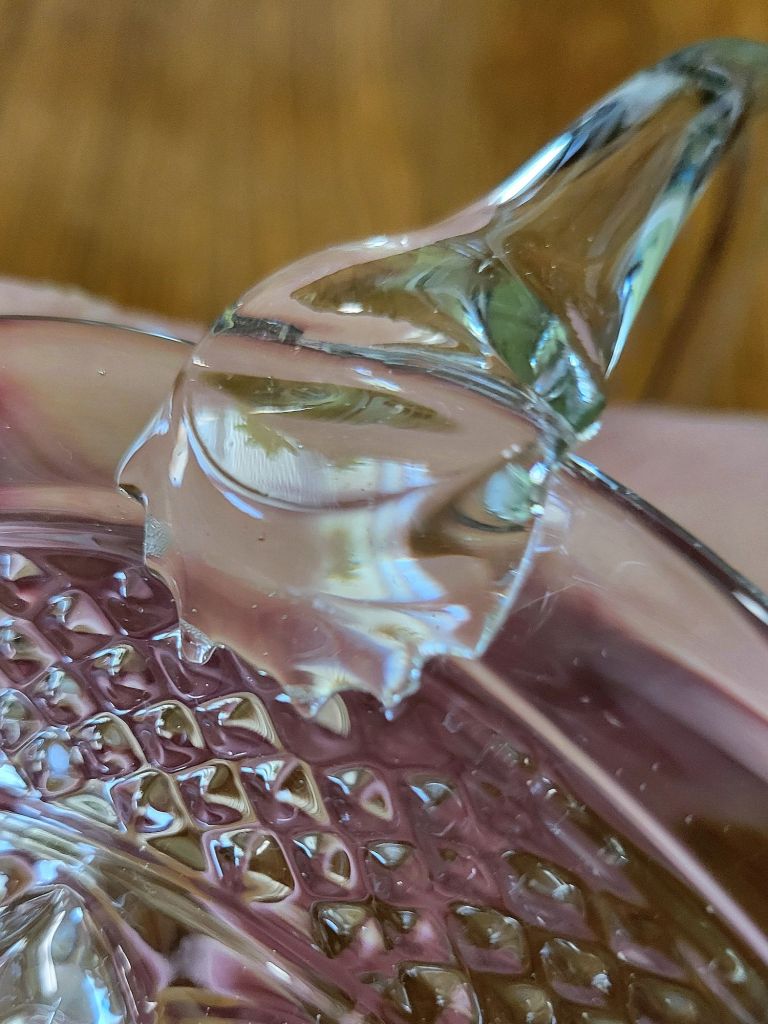a close-up view of a pressed glass basket base, mimicking Wexford by Anchor, showing one of the handle joints pulled off of position.