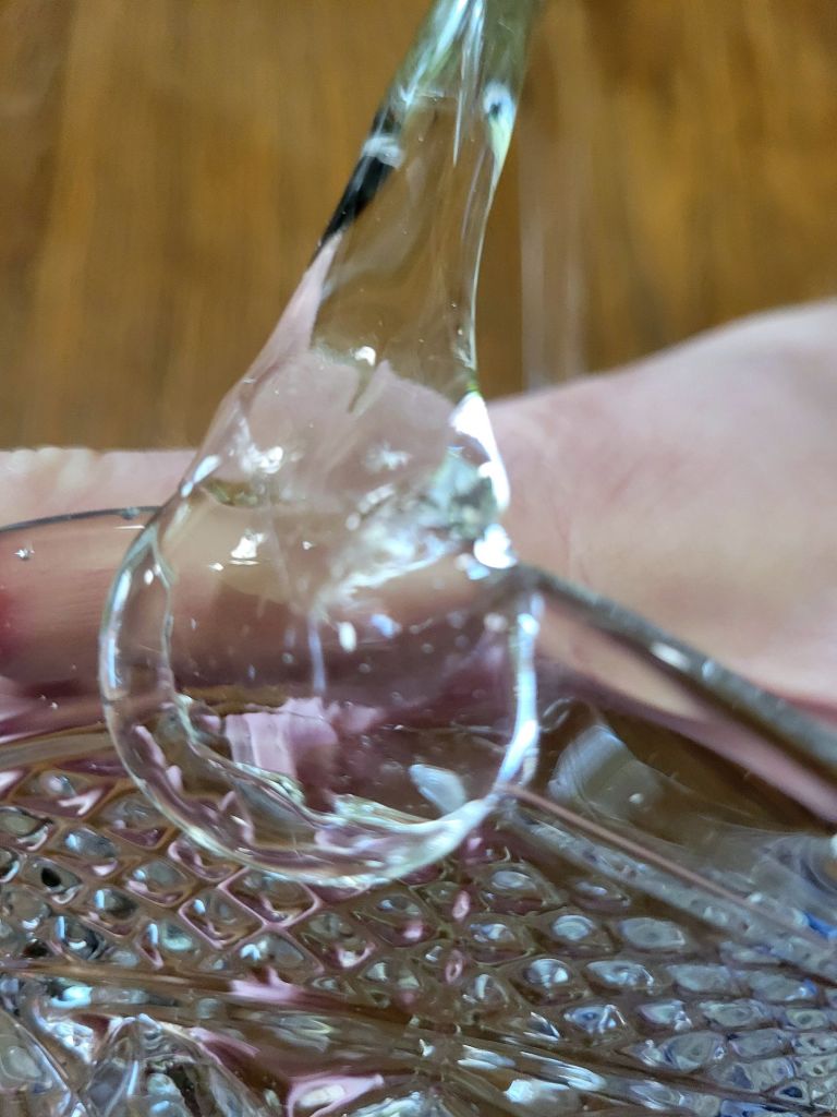 a close-up view of a pressed glass basket base, mimicking Wexford by Anchor, showing one of the handle joints cleanly on position.