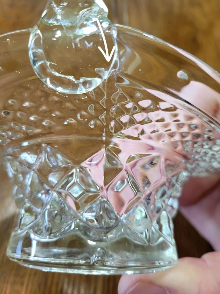 a close-up view of a pressed glass basket base, mimicking Wexford by Anchor Hocking, showing a mold seam in the glass from the manufacturing process.