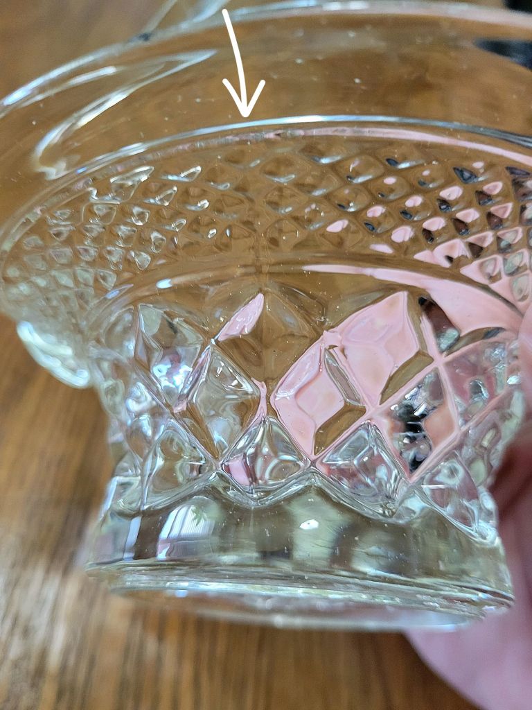 a close-up view of a pressed glass basket base, mimicking Wexford by Anchor Hocking, showing a mold seam in the glass from the manufacturing process.