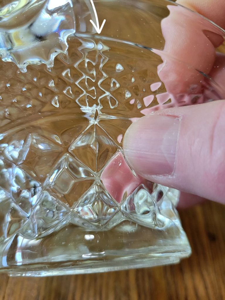 a close-up view of a pressed glass basket base, mimicking Wexford by Anchor Hocking, showing a mold seam in the glass from the manufacturing process.
