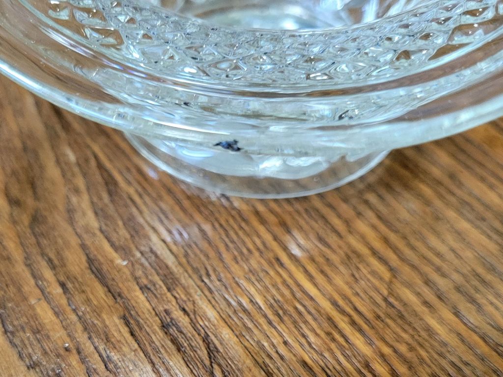 a close-up view of a pressed glass basket base, mimicking Wexford by Anchor, showing a flaw in the glass.