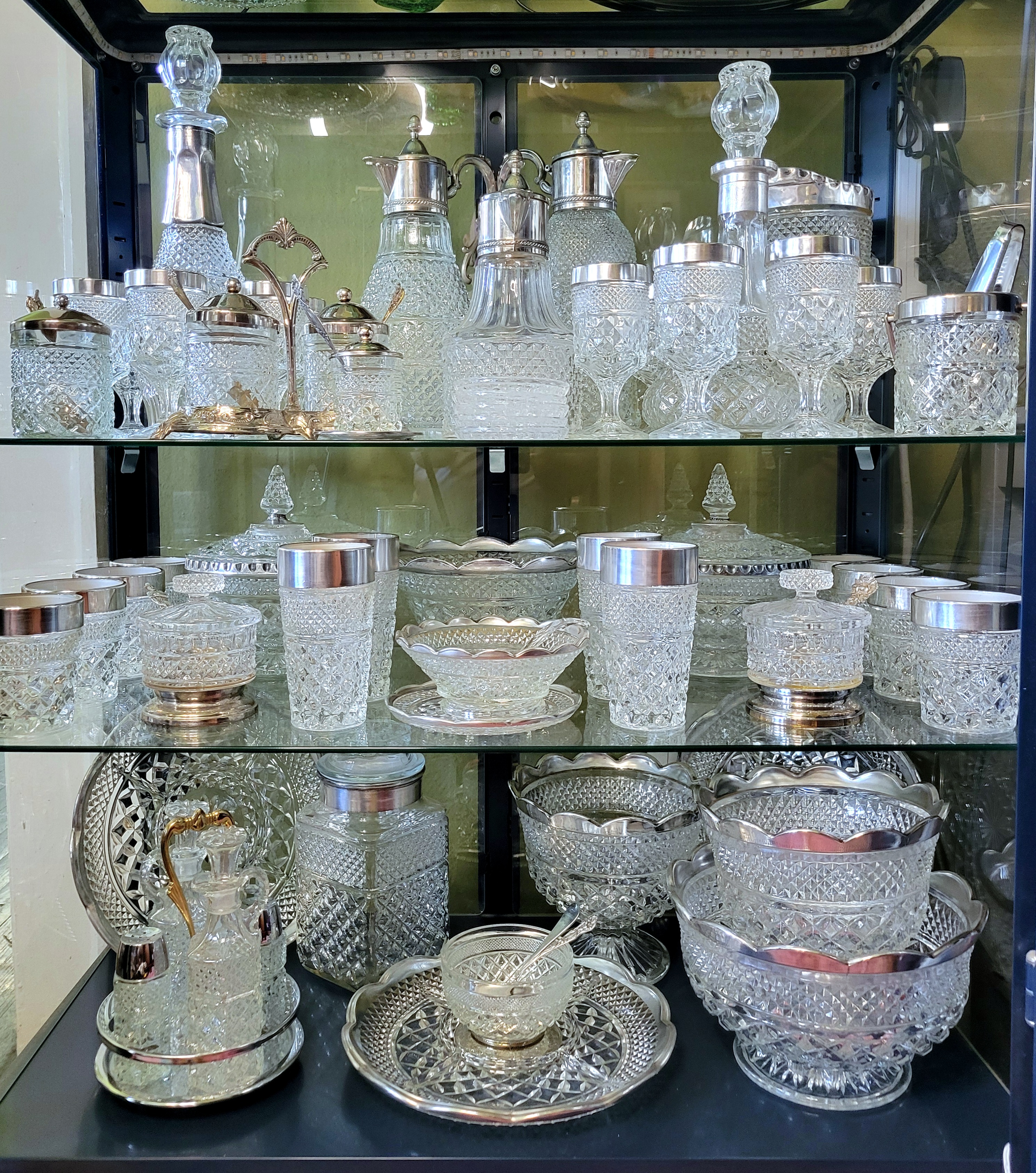 the open display case, showing all three shelves of silver-trimmed Wexford glassware, including some silver-plated lookalikes and a chrome-plated go-with.