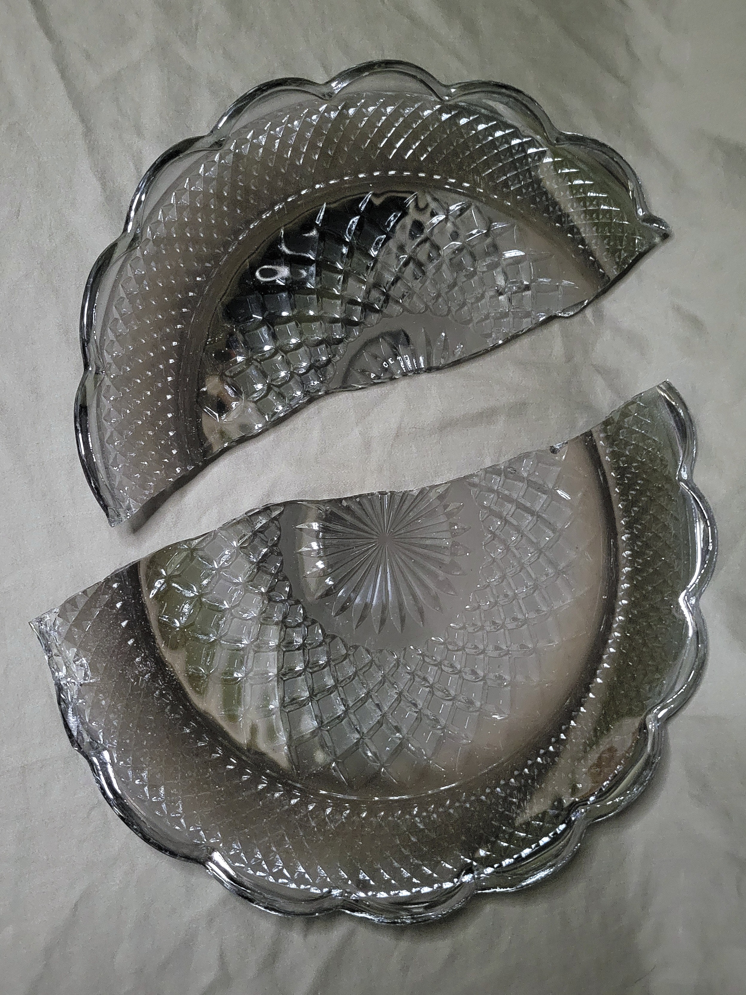 the broken platter laid out in the two parts, the dark color and a cast of iridescent is clearly visible.