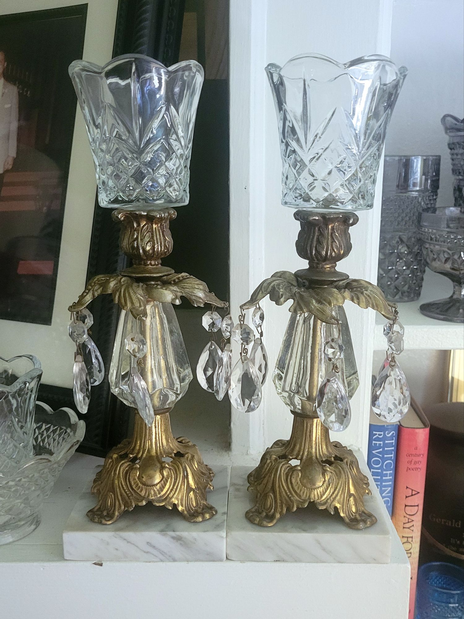 two Hollywood Regency-style candlesticks made of marble, gold-toned metal castings, resin, and glass chandelier baubles. they each hold a Cambridge peg votive by HOMCO. 
