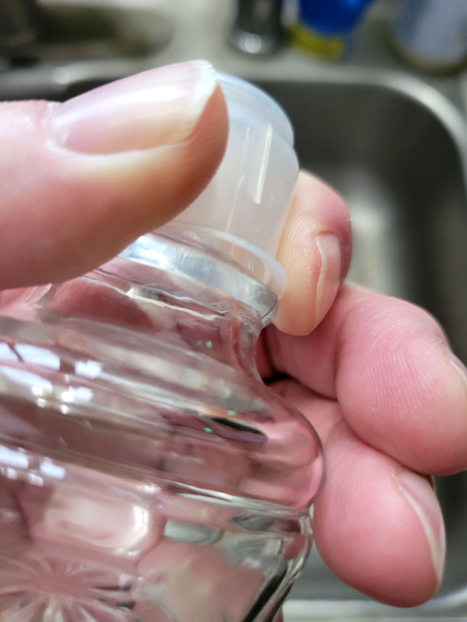 a decanter stopper held in my hand, squeezed in a way that makes a gap between the plastic gasket and the glass stopper